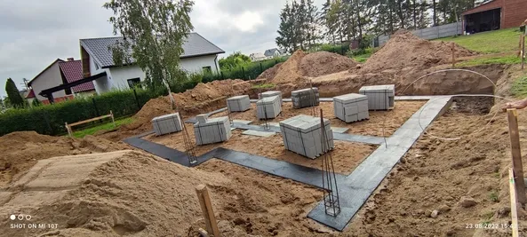 Ławy fundamentowe z izolacją poziomą i bloczkami betonowymi przygotowanymi do murowania