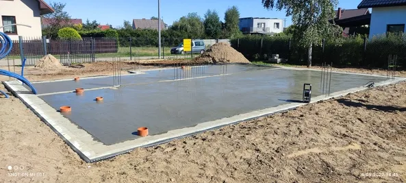 Świeżo zabetonowana płyta fundamentowa domu jednorodzinnego z wyprowadzonymi instalacjami