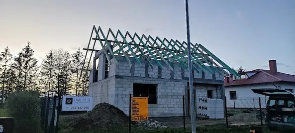 Więźba dachowa z impregnowanego drewna na domu z banerem DAR-BUD